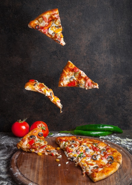 Side view pizza with pepper and tomato and pizza slices in board cookware