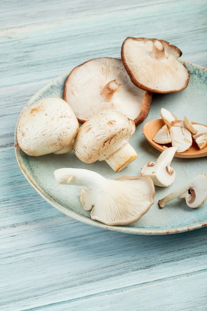 Free Photo side view of plate with whole fresh mushrooms on rustic wooden surface