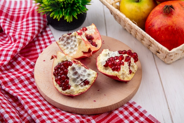 Side view of pomegranate slices on a stand with a red checkered towel on a white surface