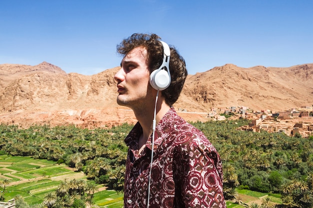 Free Photo side view portrait of young man listening to music in oasis