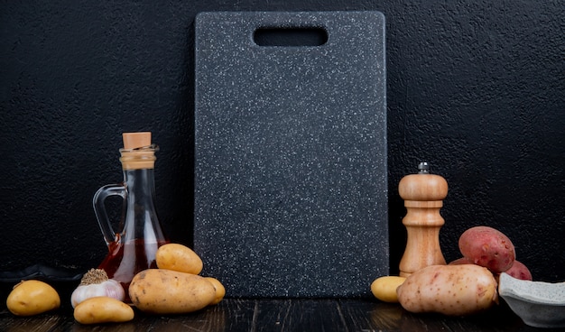 Free Photo side view of potatoes with melted butter garlic and cutting board on wooden surface and black background