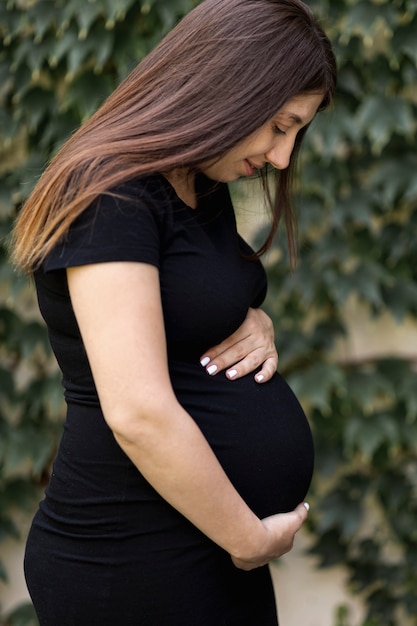 Free photo side view pregnant woman in black dress outdoors