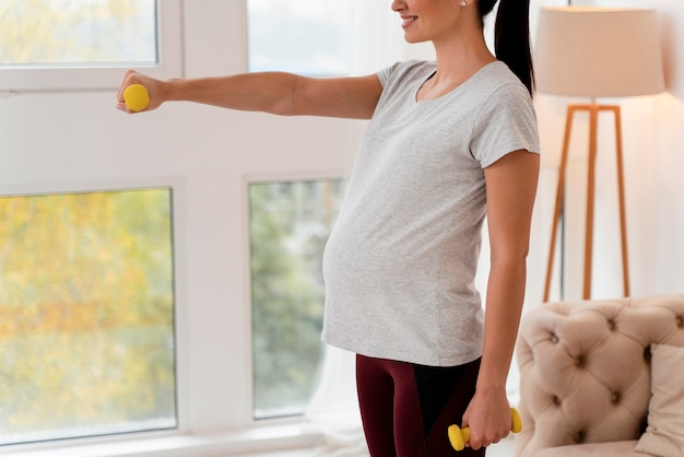 Side view pregnant woman training with weights