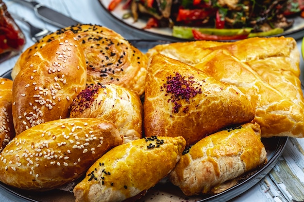 Side view puff pastries with ground meat sesame seeds and shortcakes filled with mashed potato on the table