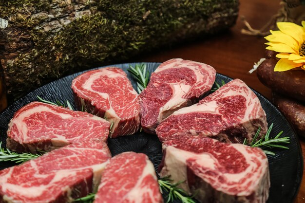 Side view raw marbled steak meat with rosemary on a stand