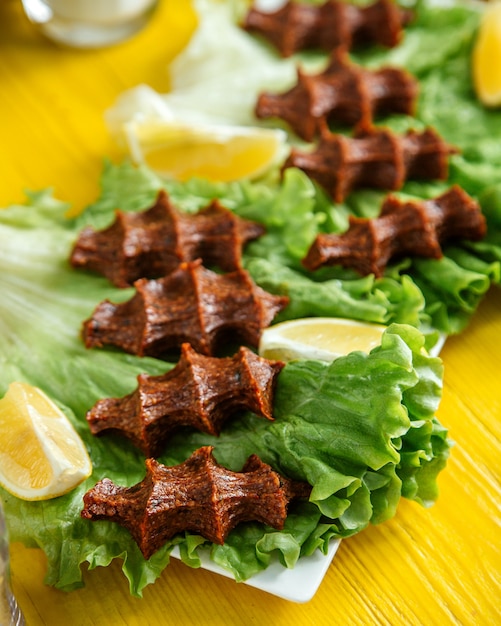 Side view of a raw meat dish in turkish cuisines cig kofte with lemon on lettuce