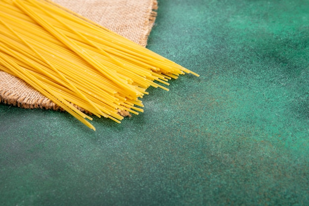 Free photo side view of raw spaghetti on a green surface