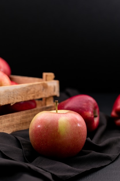 Side view red apples in crate with black cloth on black