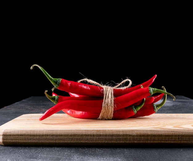 Side view red chili pepper on wooden cutting board on black