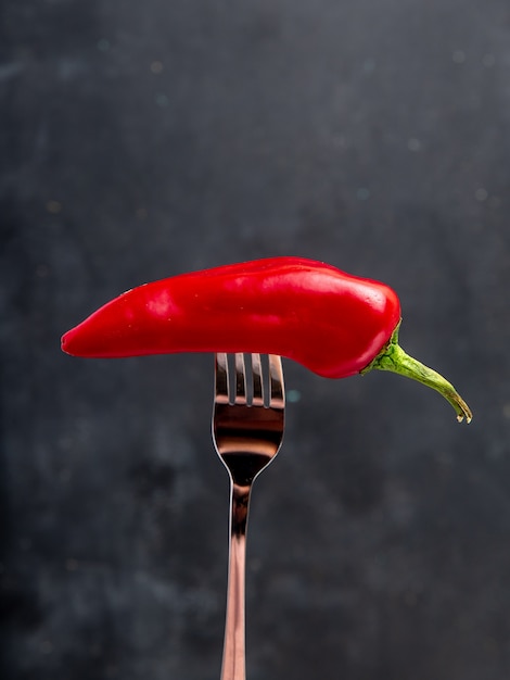 Free Photo side view of red pepper on fork on black background with copy space