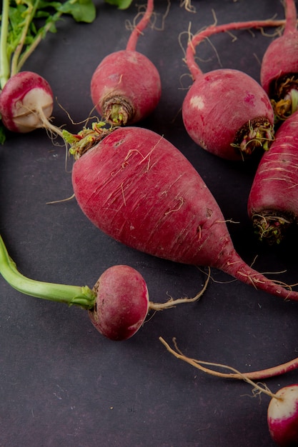 Free Photo side view of red radishes on maroon background