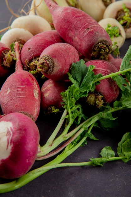 Free photo side view of red radishes with white ones on maroon background