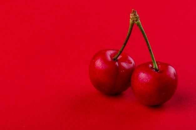 Free Photo side view of red ripe cherry with water drops isolated on red with copy space