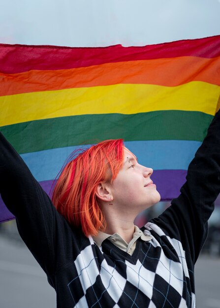 Side view redhead non binary person holding up a lgbt flag