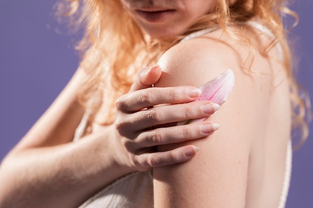 Side view of a redhead woman posing with a flower petal