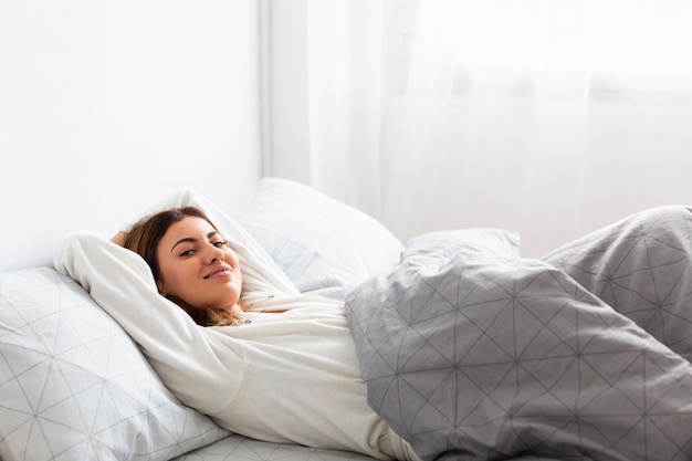 Side view of relaxed woman in bed in pajamas