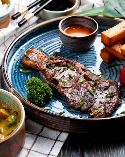 Free photo side view of roasted beef with spicy sauce and grilled tomato with fried bread sticks on a plate