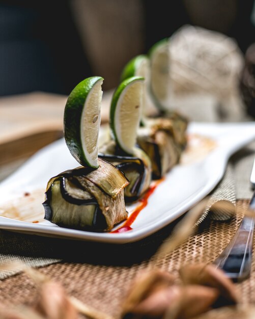 Side view rolled fried eggplant with lime slices