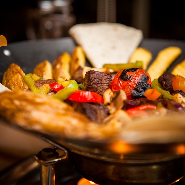 Side view sac with meat and fried potatoeslavash in table on restaurant