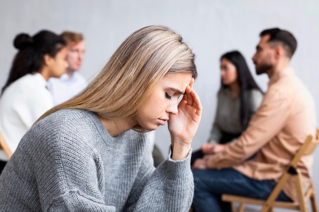 Free photo side view of sad woman at a group therapy session