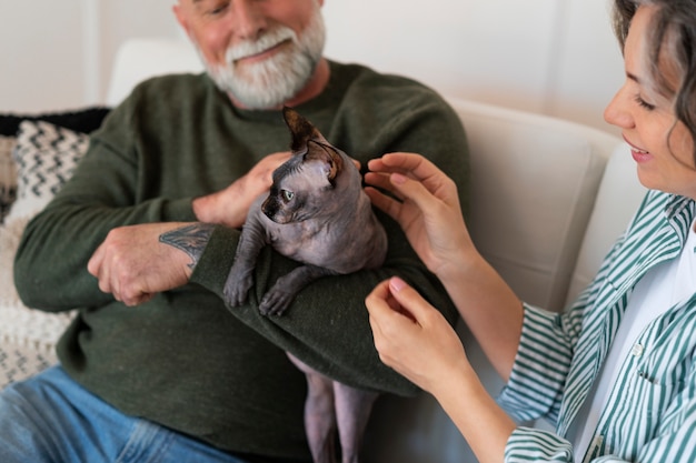 Free Photo side view senior couple with cat at home