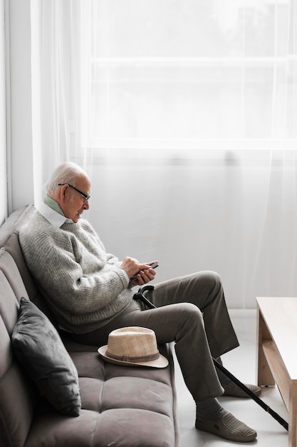 Side view of senior man in a nursing home using smartphone