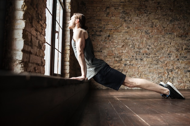 Side view of a serious healthy young sportsman doing exercises