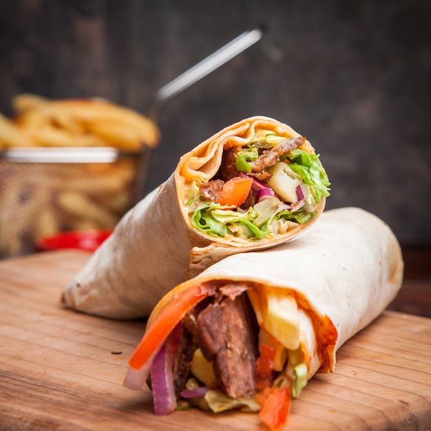 Free Photo side view shawarma with fried potatoes in board cookware