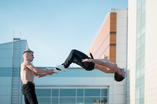 Free Photo side view of shirtless hip hop artists dancing outside together