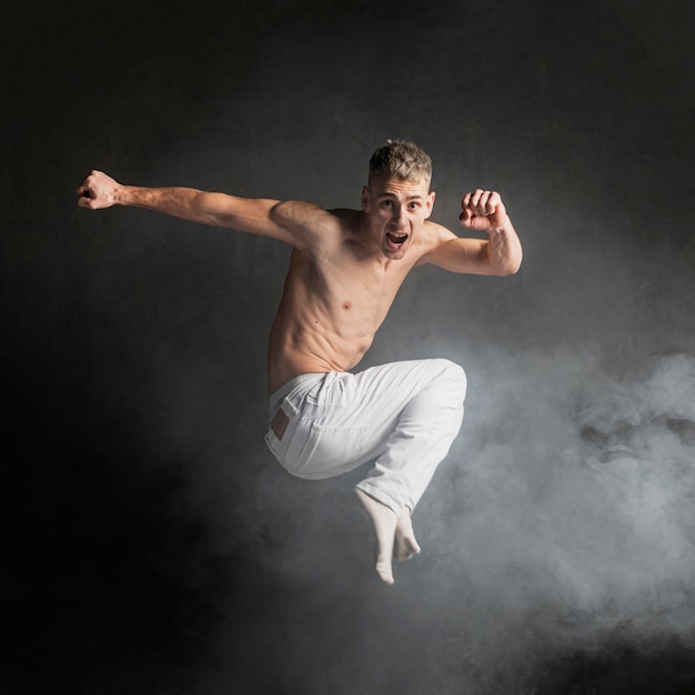 Free photo side view of shirtless male dancer posing in mid-air