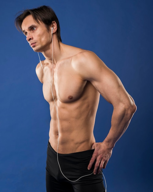 Side view of shirtless muscled man wearing headphones