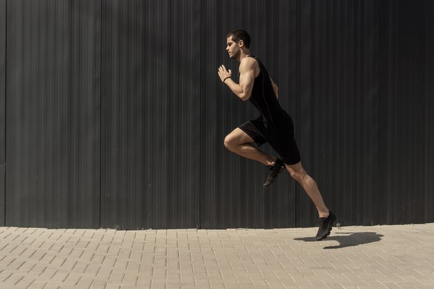 side view shot of a fit young, athletic man jumping and running.