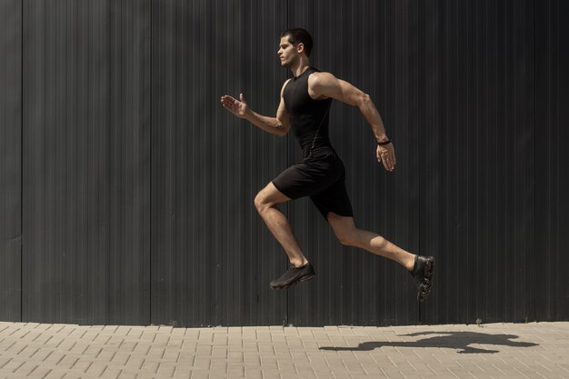 side view shot of a fit young, athletic man jumping and running