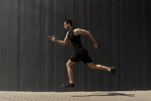 side view shot of a fit young, athletic man jumping and running.