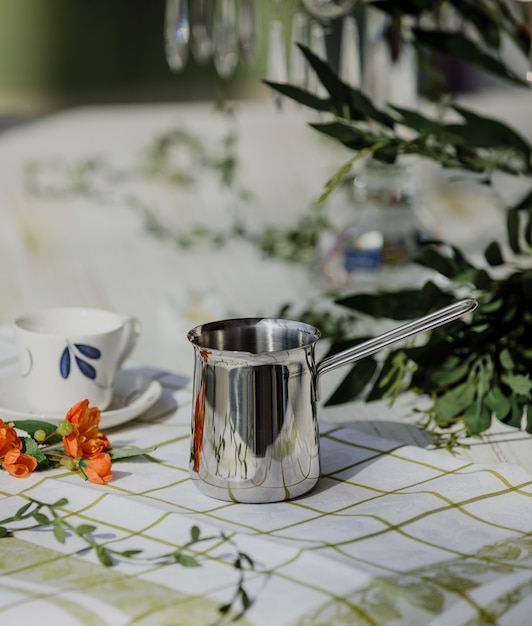 Free photo side view of silver coffee turk pot on a kitchen table