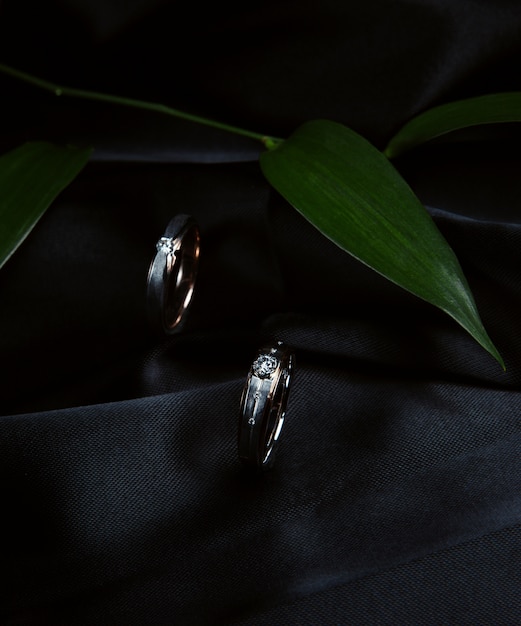 Free photo side view of silver wedding rings on black wall