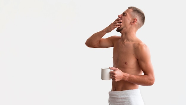 Free photo side view of sleepy shirtless man in the morning with coffee