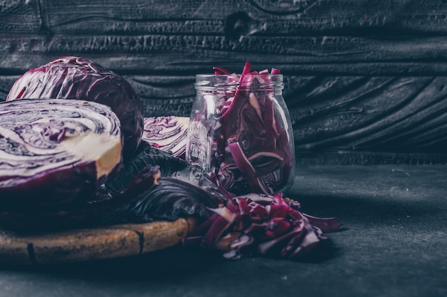 Side view sliced red cabbage in jar on dark textured background. vertical