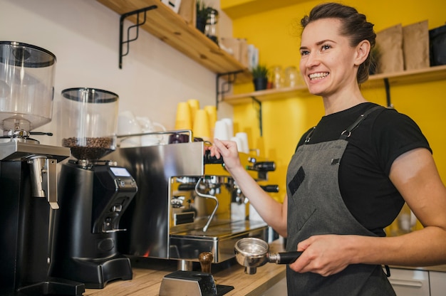 Side view of smiley barista using coffee machine