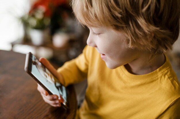 Side view of smiley boy using smartphone at home