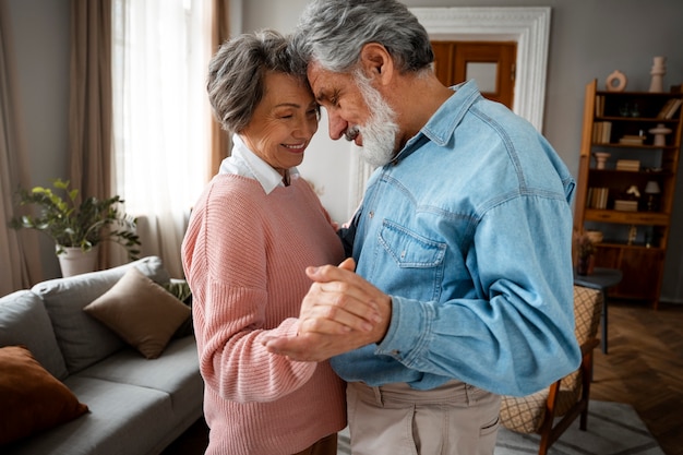 Side view smiley couple dancing at home