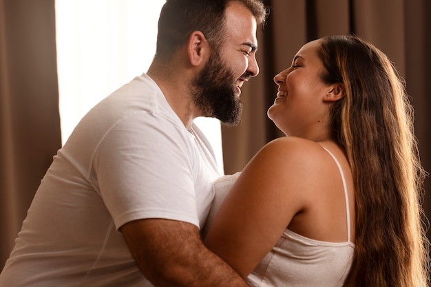 Free photo side view smiley couple indoors