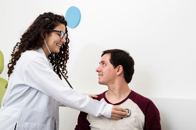 Side view smiley doctor checking a patient