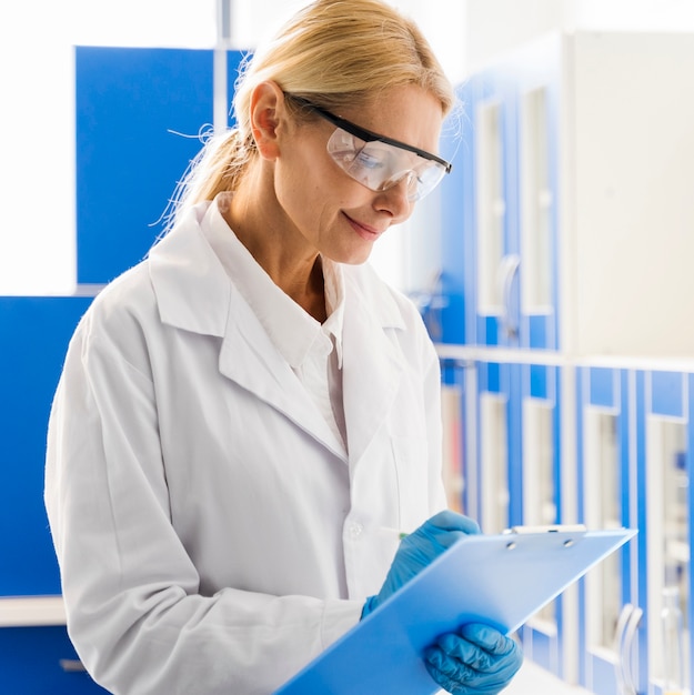 Free photo side view of smiley female scientist with surgical gloves in the laboratory