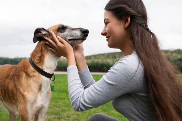 Free photo side view smiley girl petting dog