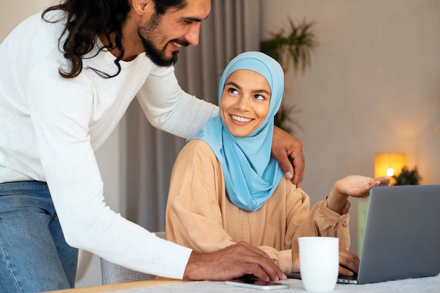 Side view smiley islamic couple with laptop