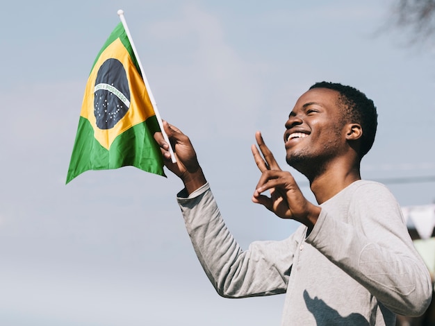 Free photo side view smiley man holding brazilian flag