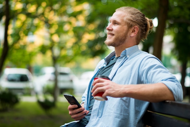 Free photo side view of smiley man outdoors with smartphone