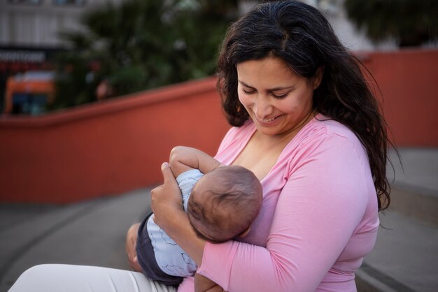 Side view smiley mother breastfeeding outside