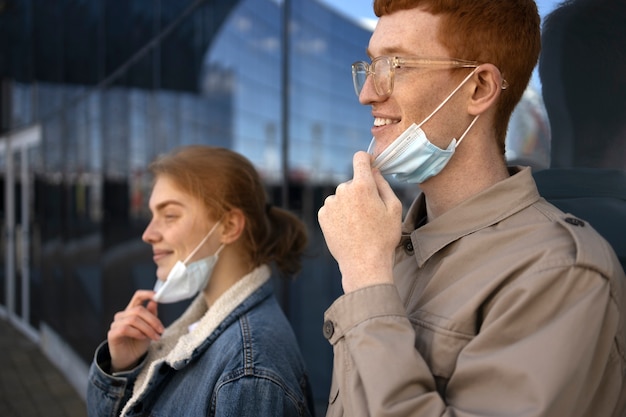 Side view smiley people taking masks off